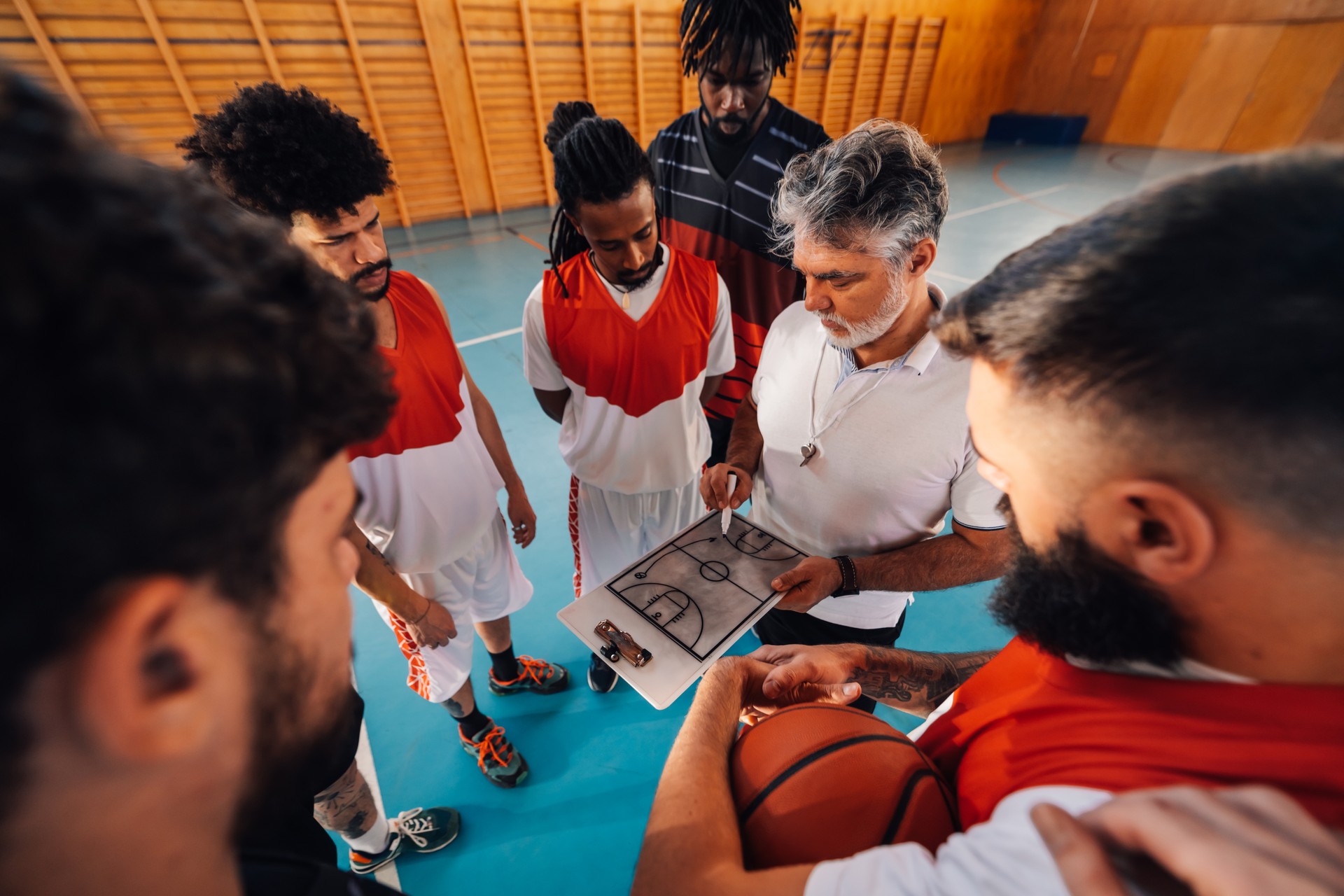 Basketball trainer working on game tactic with his interracial team.